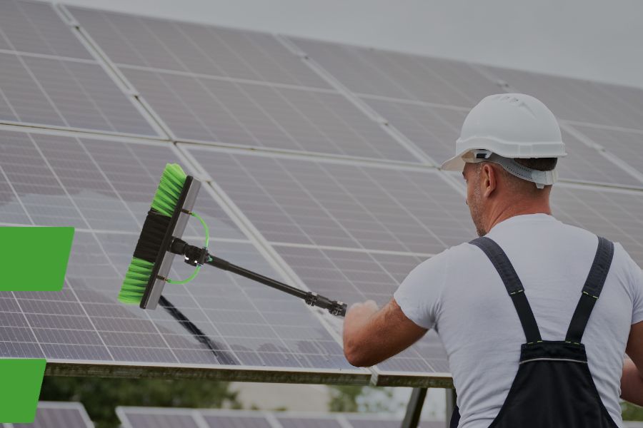 Jemand reinigt Solarmodule mit einer Waschbürste